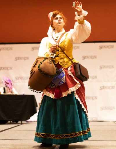 Whitney Sews, the Soonercon 30 Winner of Costume Contest Best of Show poses in her Francesca cosplay from Avalon Code. She is holding up a glass vile and inspecting it.
