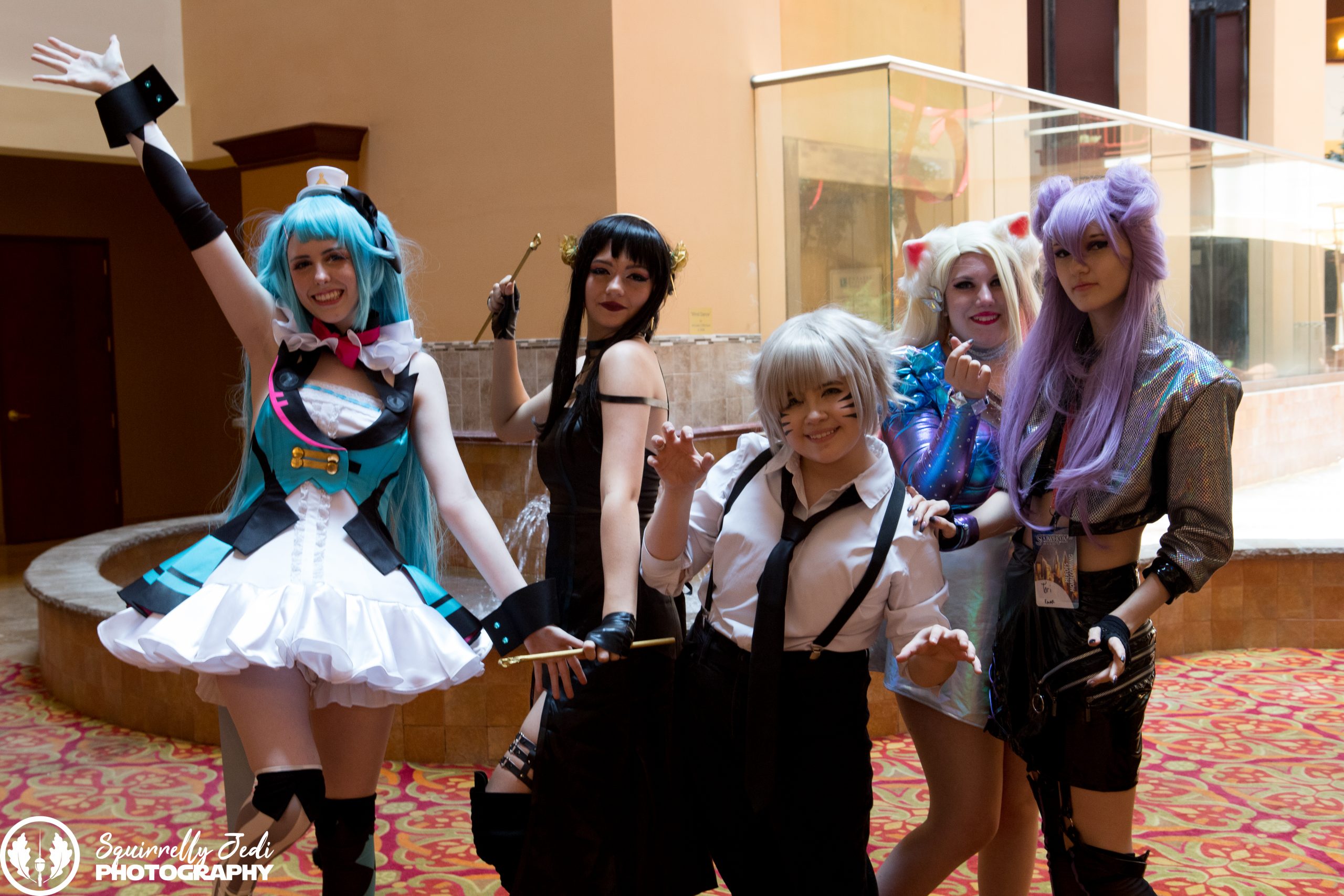 Five cosplayers in anime costumes pose for a photo.