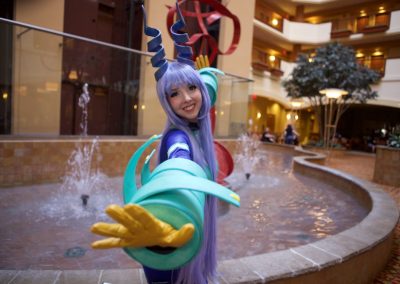 Cosplayer in Nejire cosplay from My Hero Academia poses with arms outstretched in front of the fountain at the Embassy Suites Norman.