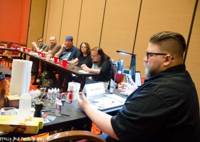 A teacher is speaking to a class of seated students who are learning how to paint miniatures.