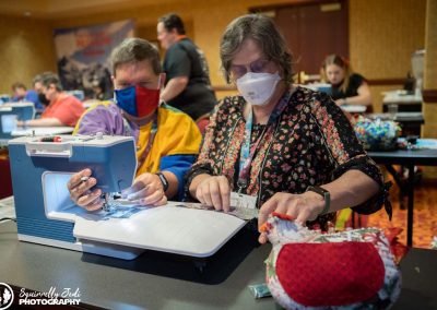 A teacher sites next to a student who is learning how to sew at a Bernina sewing machine.