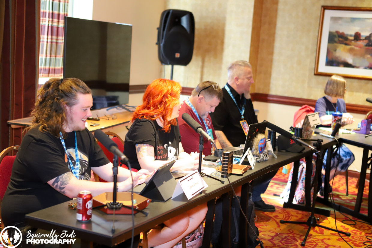 guest panelists talk into mics at a live dungeons and dragons game