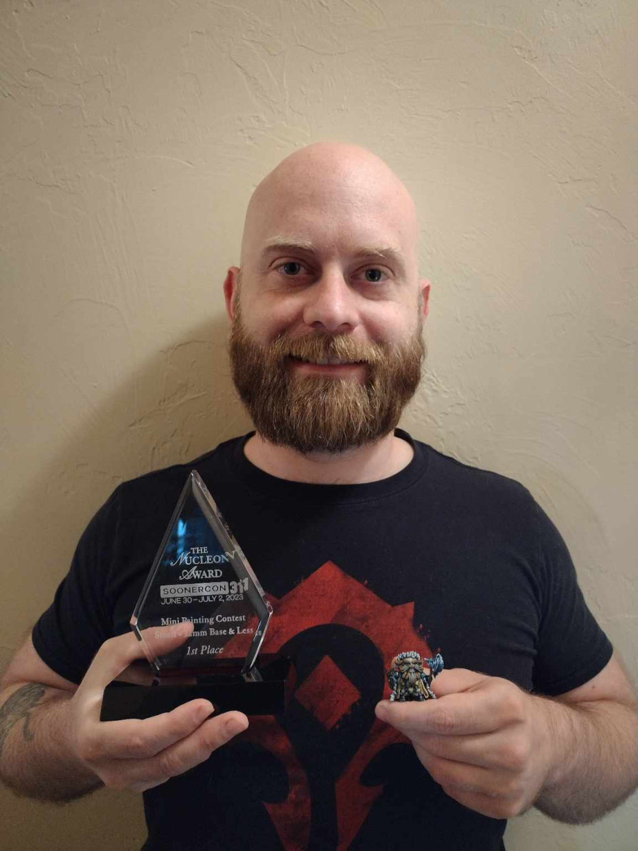 first place winner of small base miniatures poses with the winning miniature and trophy