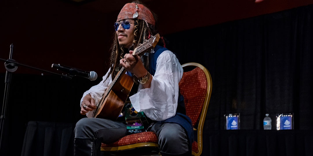Artist performs on a guitar dressed as Jack Sparrow