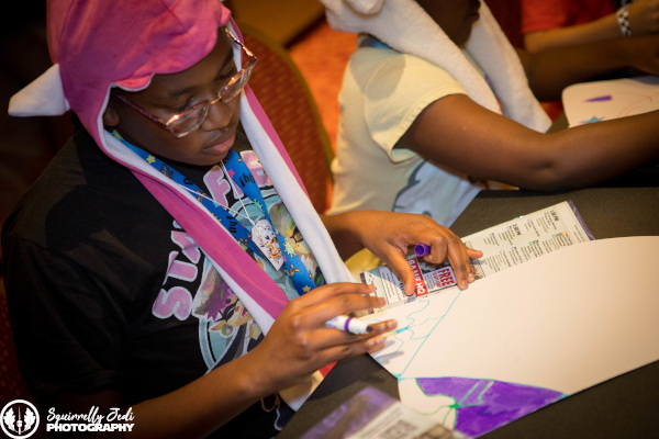 A kid with a purple marker looks at his art project.